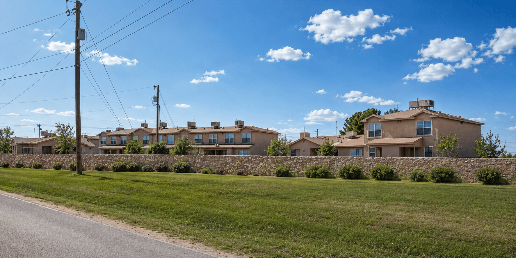 A row of houses with a stone wall in front.